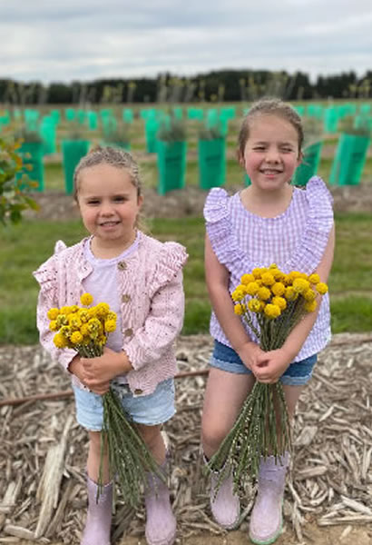2 girls standing in field of growing plants